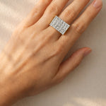 Hand wearing a diamond ring on a neutral background