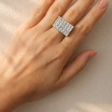 Hand wearing a diamond ring on a neutral background