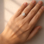 Hand wearing a diamond ring on a neutral background
