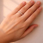Hand wearing a rose gold diamond ring on a neutral background
