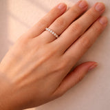 Hand wearing a rose gold diamond ring on a neutral background