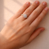 Hand wearing a diamond ring on a neutral background