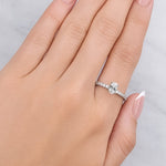 Hand wearing a silver ring with a diamond on a light grey background at LeGassick.