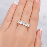Silver ring with five diamonds on a hand with light pink nail polish against a light grey background at LeGassick.