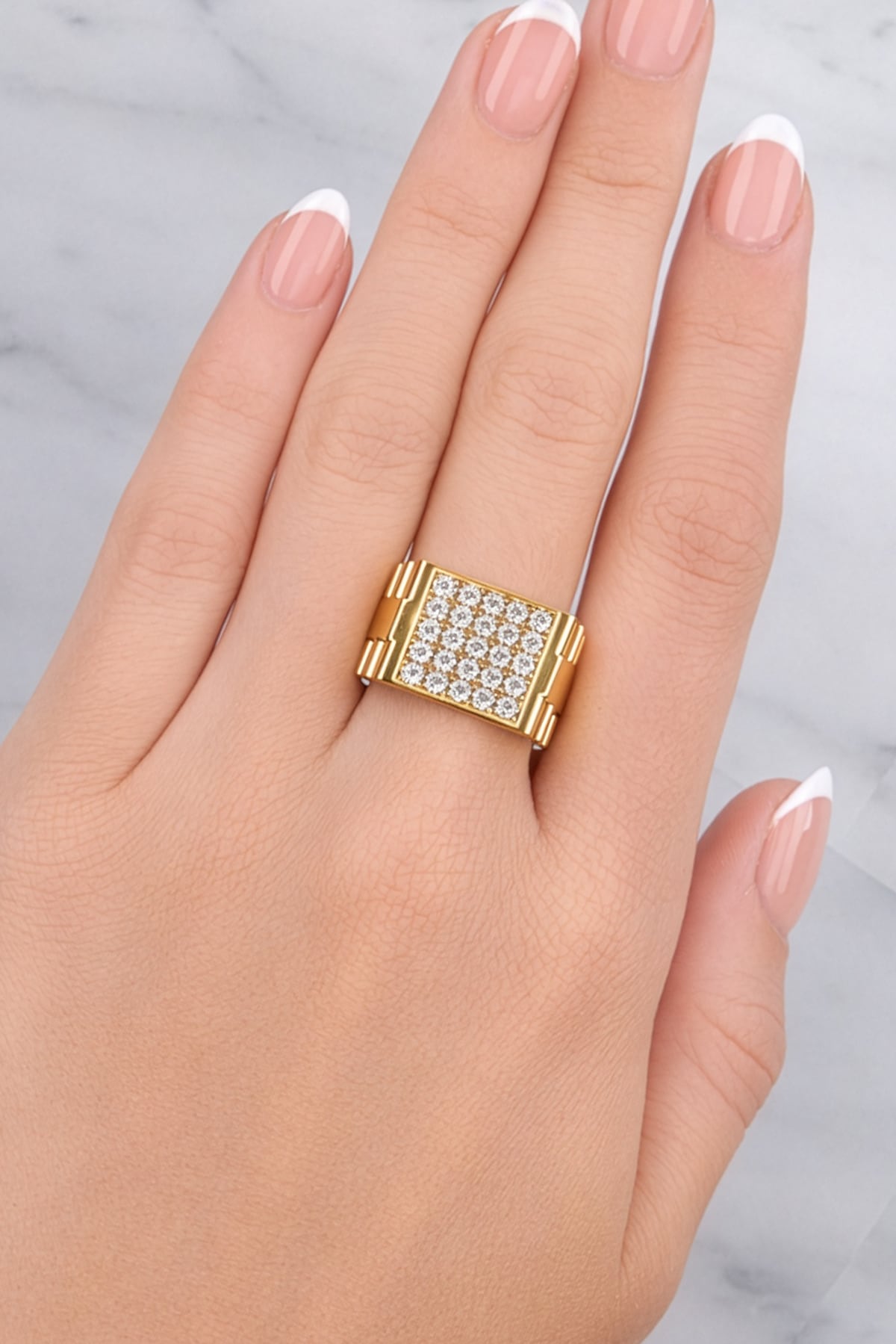 Gold ring with diamonds on a hand against a light background at LeGassick Showroom.