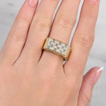 Gold ring with diamonds on a hand against a neutral background at LeGassick showroom