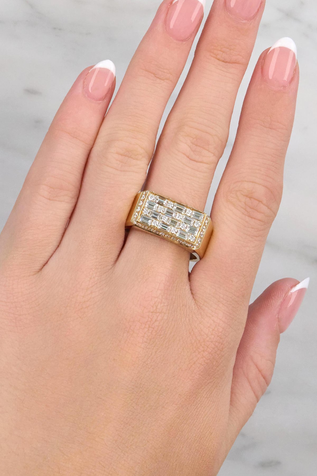 Gold ring with diamonds on a hand against a neutral background at LeGassick showroom