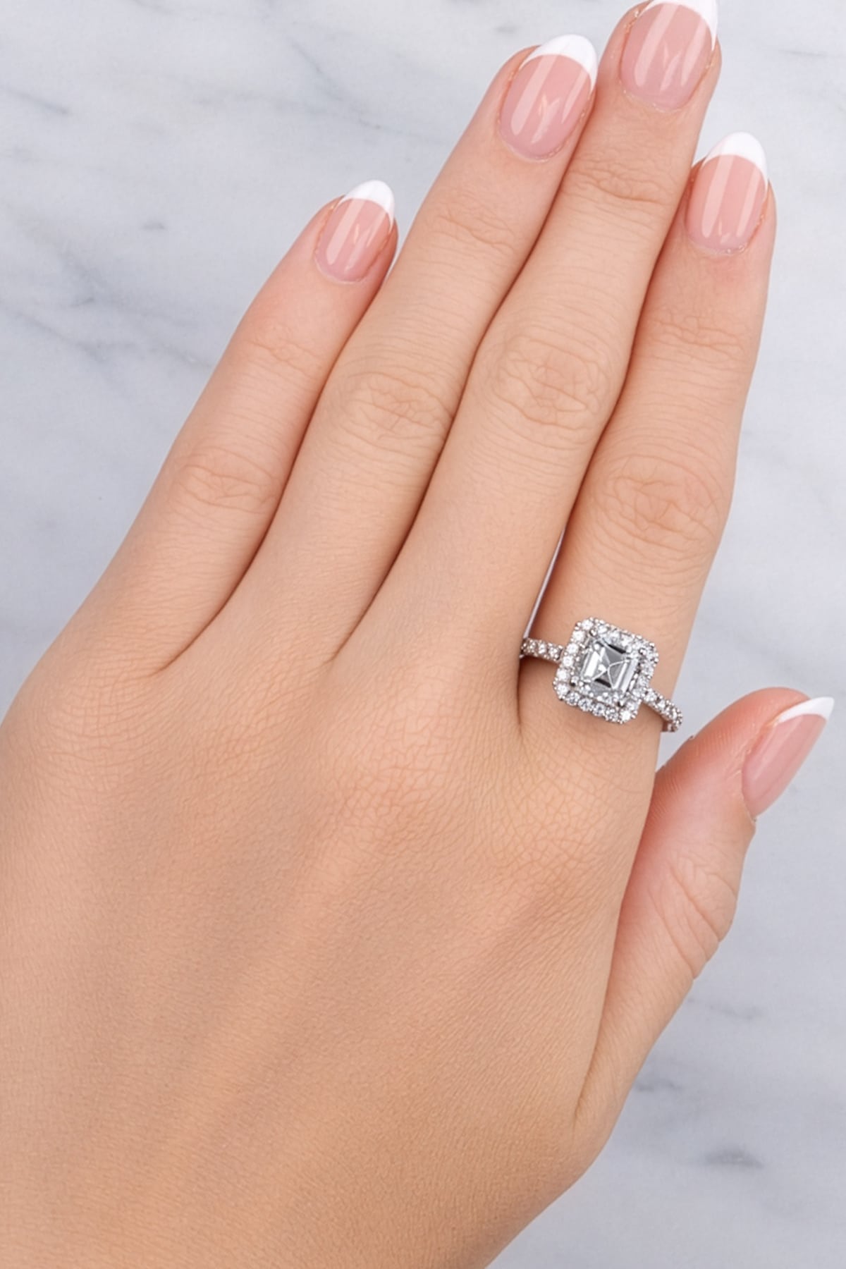 Hand wearing a diamond ring on a neutral background at LeGassick.