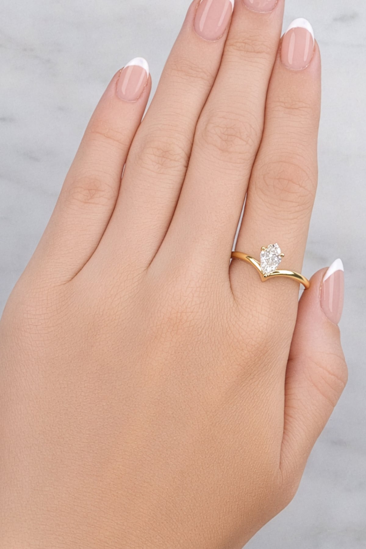 hand wearing old ring with a pear-shaped diamond on a white background
