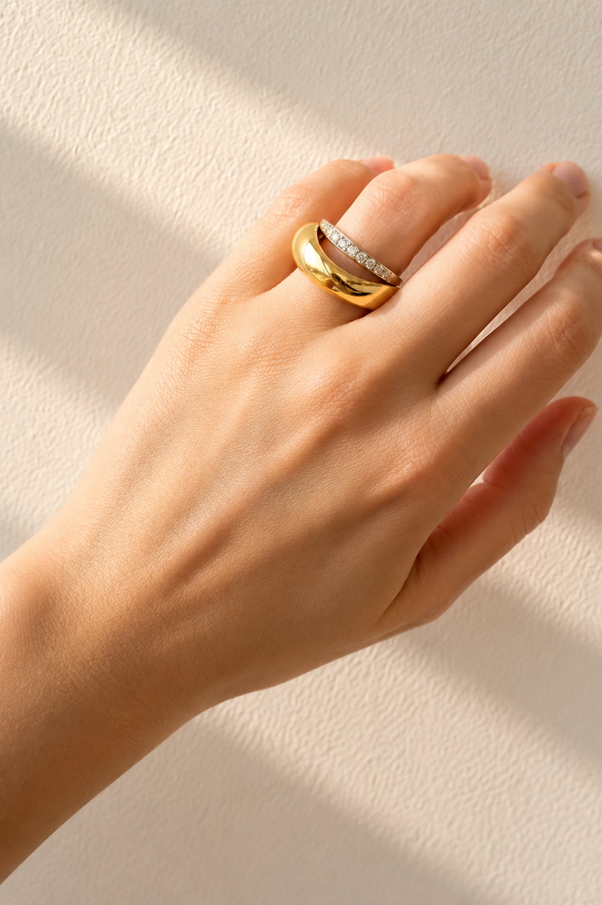 Hand wearing a gold ring on a light gray background
