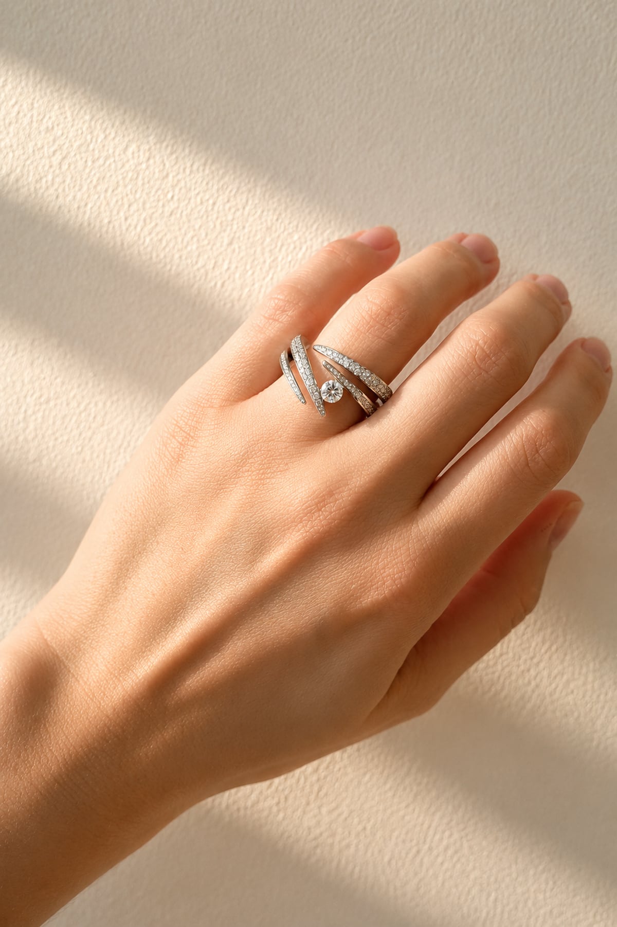 Hand wearing a white gold and diamond ring on a neutral background