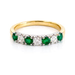 Gold ring with emeralds and diamonds on a white background