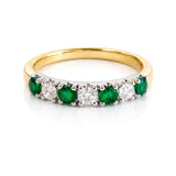 Gold ring with emeralds and diamonds on a white background