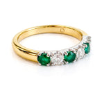 Gold ring with emeralds and diamonds on a white background