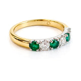 Gold ring with emeralds and diamonds on a white background