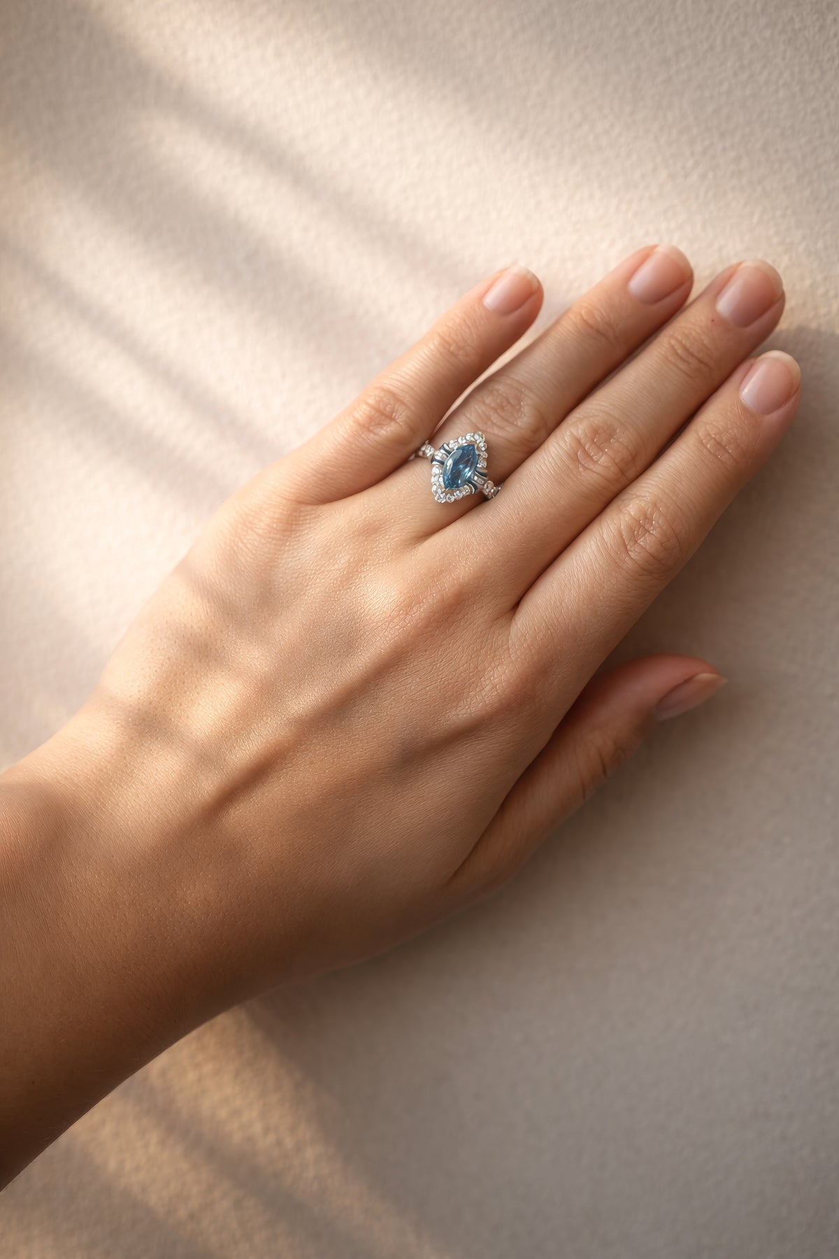 Hand wearing a ring with a blue gemstone on a neutral background at LeGassick.