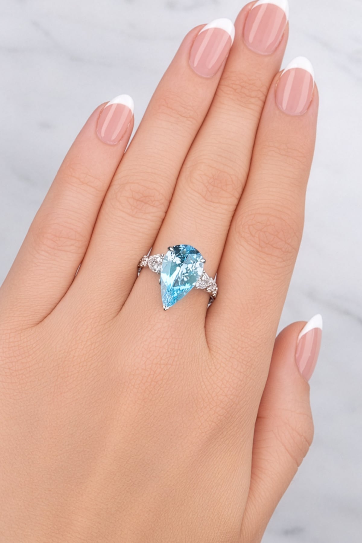 Lady's hand wearing a Pear Aquamarine & Diamond Ring set in 18ct White Gold at LeGassick.