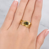 Gold ring with a green gemstone on a hand against a light background