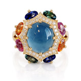 Luxury ring with a large blue gemstone surrounded by smaller multicolored gems on a white background