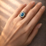 Ring with a blue gemstone on a hand against a brown background