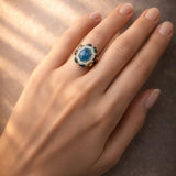 Ring with a blue gemstone on a hand against a brown background