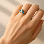 Hand wearing London Blue Topaz Toi et Moi Yellow Gold Ring on a light background