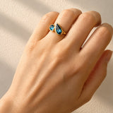 Hand wearing London Blue Topaz Toi et Moi Yellow Gold Ring on a light background