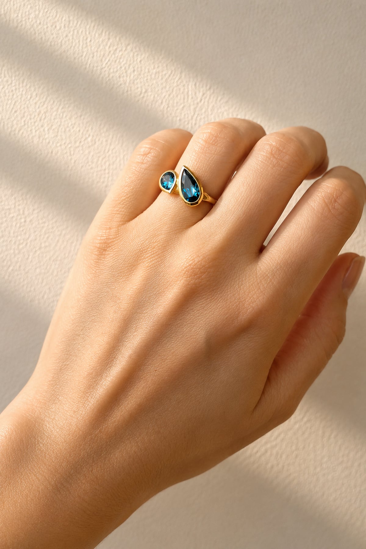 Hand wearing London Blue Topaz Toi et Moi Yellow Gold Ring on a light background