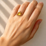 Hand wearing a Citrine & Diamond Leaf Motif Ring in Yellow Gold on a beige background