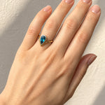 Hand wearing a London Blue Topaz Ring in Yellow & White Gold on a beige background