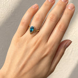 Hand wearing a London Blue Topaz Ring in Yellow & White Gold on a beige background