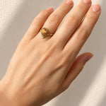 Hand wearing a Pear Cut Bezel Set Citrine Ring in Yellow Gold on a light background