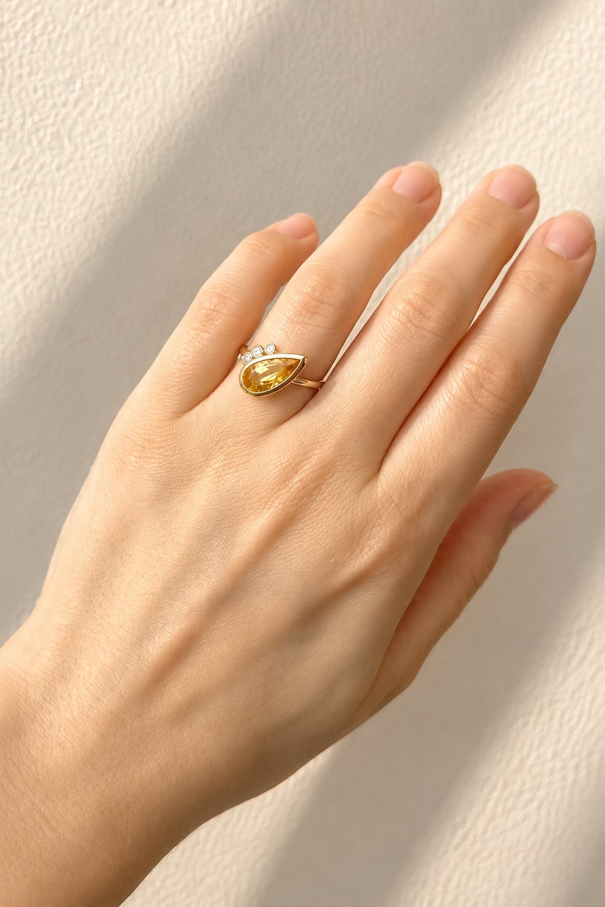Hand wearing a Citrine & Diamond Dress Ring in Yellow Gold on a light background