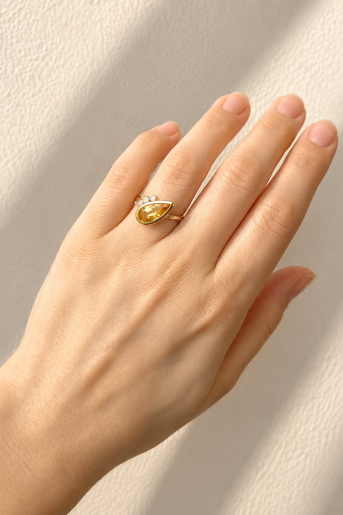 Hand wearing a Citrine & Diamond Dress Ring in Yellow Gold on a light background