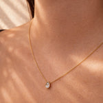 Gold necklace with a diamond teardrop pendant on a person's neck at LeGassick