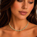 A close-up of a woman wearing a delicate gold and yellow diamond necklace, looking down with a serene expression.
