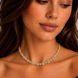 A close-up of a woman wearing a delicate gold and yellow diamond necklace, looking down with a serene expression.