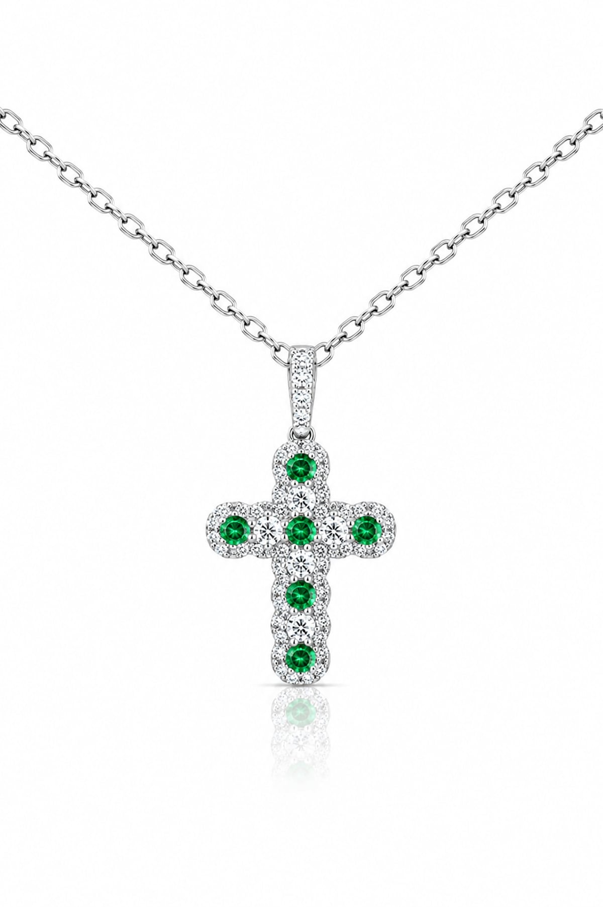 A white gold cross pendant featuring a central cluster of round green emeralds surrounded by pavé-set clear diamonds, shown on a white background with a soft reflection.