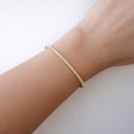Gold diamond Bangle on a wrist against a light background