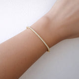Gold diamond Bangle on a wrist against a light background