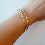 Gold bracelet on a wrist against a light background