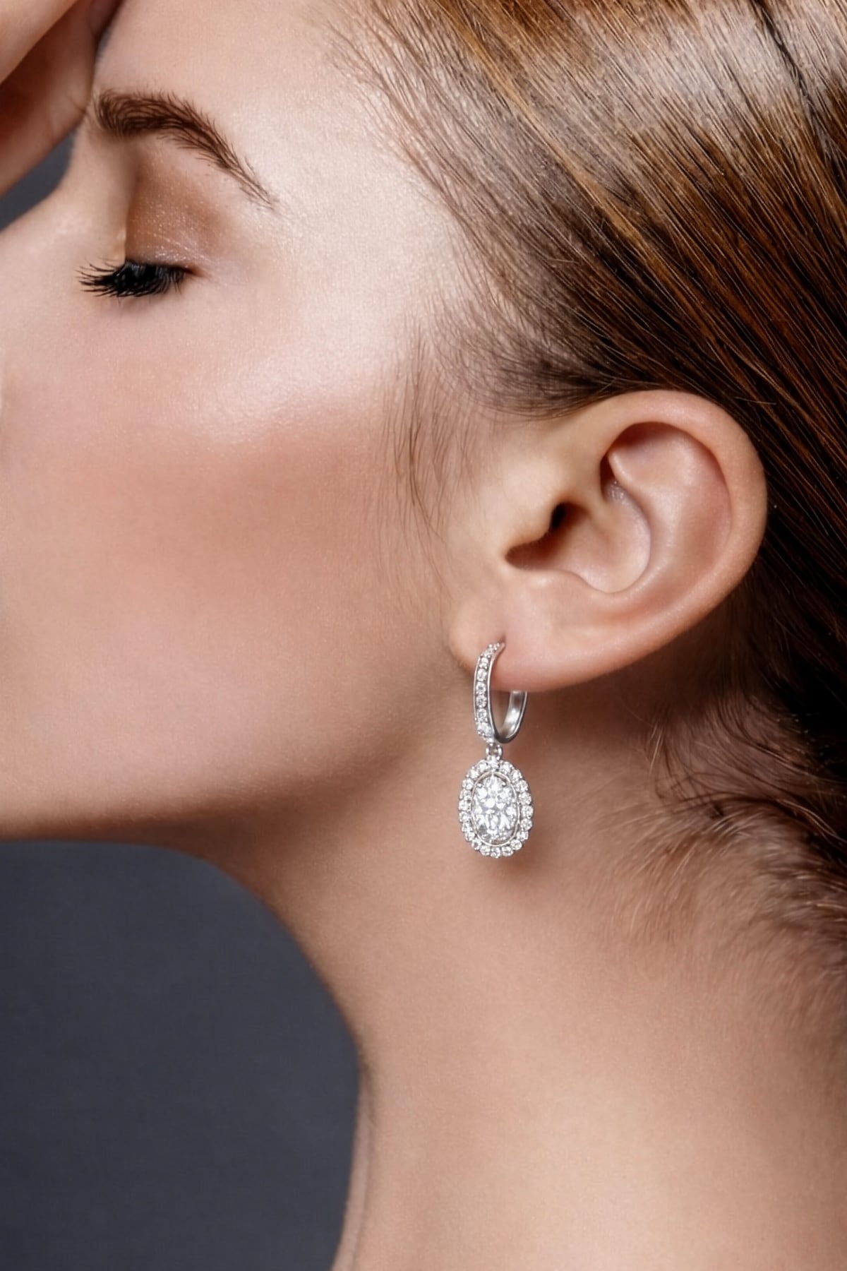 Close-up of a woman wearing a diamond drop earring with a dark background at LeGassick.