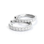 Pair of white gold hoop earrings with clear diamonds on a white background