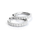 Pair of white gold hoop earrings with clear diamonds on a white background