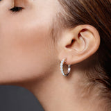 Pair of white gold hoop earrings with clear diamonds on a lady's ear