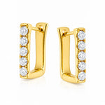 A pair of gold huggie hoop earrings with a vertical row of round-cut clear diamonds on the front, set against a plain white background.