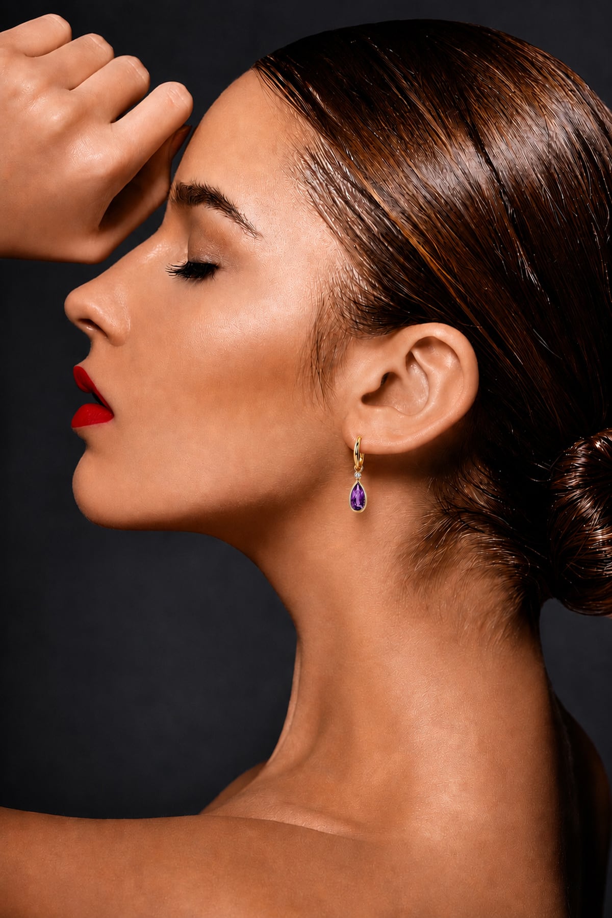 Lady wearing Amethyst & Diamond Drop Earrings in Yellow Gold on a grey background