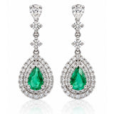 Pair of 18ct white gold Colombian emerald and diamond drop earrings featuring pear-shaped green emeralds surrounded by double halos of round brilliant-cut diamonds.