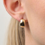 Gold hoop earring worn by a person with a neutral background
