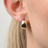 Gold hoop earring worn by a person with a neutral background